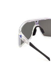 Przezroczyste okulary sportowe z przezroczystymi oprawkami, ciemnymi szkłami, czarnymi nakładkami na nos i czarnymi zakończeniami zauszników, pokazane na białym tle.