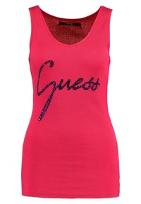 Lyserød ribbet tanktop med v-hals og et sort, glitrende "Guess" logo på forsiden. Strækstof med en tætsiddende pasform.