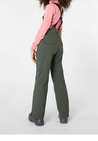 Pantaloni da neve impermeabili verdi con strisce regolabili, due tasche posteriori e un design affusolato. Indossati sopra una maglietta a maniche lunghe rosa chiaro.