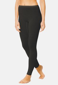 Leggings noirs au design ajusté, fabriqués en matériau lisse et extensible, présentant une taille légèrement festonnée et une longueur cheville.