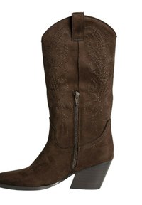 Bota de cowboy de ante marrón con puntera afilada, costuras decorativas y cremallera lateral. Presenta un tacón de madera en contraste.
