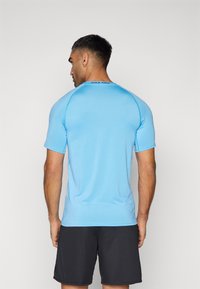 Blaues sportliches Shirt mit kurzen Ärmeln und Rundhalsausschnitt, aus glattem Stoff. "Nike Pro" Branding am hinteren Halsausschnitt.