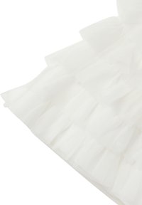 Tessuto di tulle bianco con volant sovrapposti e una morbida texture trasparente. Il materiale appare leggero e arioso, esaltando il suo design delicato.