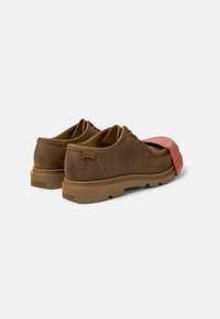 Brown leather shoes with a textured finish, accentuated by a coral-colored rubber overlay on the front, and a rubber sole.
