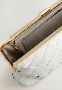 Biała pleciona skórzana kopertówka ze złotą ramką i zapięciem, otwarta, ukazująca szare tkaninowe wnętrze z małą wewnętrzną kieszenią.