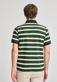 Grön och krämrandig kortärmad polo med en marinblå krage. Tillverkad av bomull med en texturerad yta; klassisk passform.