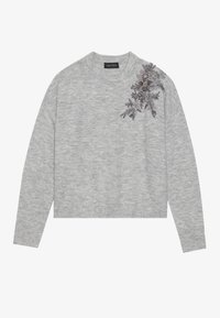 Suéter gris con un escote y puños acanalados, que presenta bordados en forma de encaje con acentos metálicos en el hombro izquierdo. Diseño simple y corto.