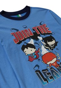 Camiseta de algodón azul con superhéroes de dibujos animados: Superman, Batman y Flash. Texto "ÚNETE A LA LIGA" en rojo negrita. Cuello redondo clásico.