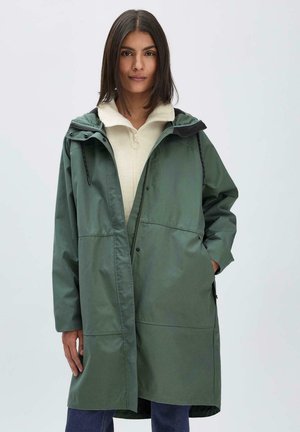 Groene, gevoerde jas met een ritssluiting aan de voorkant, zijzakken en een ontspannen pasvorm. De stof heeft een gladde textuur en bevat contrasterende zwarte accenten.