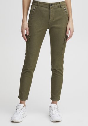 Olijfgroene cargobroek met een slim fit, voorzien van ritszakken, een knoopsluiting en enkellange boorden, gecombineerd met witte sneakers.