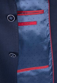 Slim-Fit-Blazer aus strukturiertem dunklem Außenstoff. Das Innere verfügt über ein glattes blaues Futter mit Punkten und einer roten Akzenttasche.