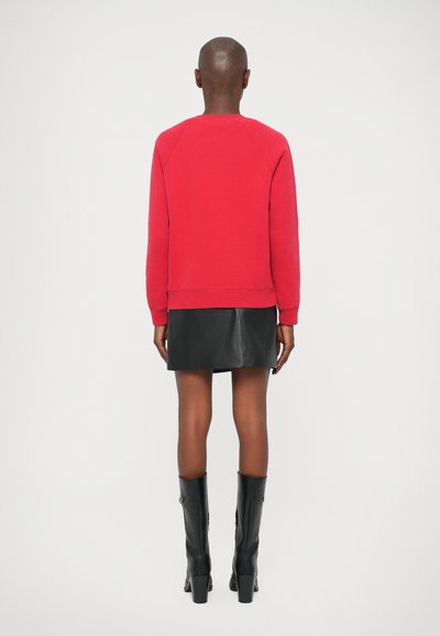 Rode sweatshirt met een zachte textuur en raglan mouwen, gecombineerd met een zwarte leren minirok en zwarte kniehoge laarzen.