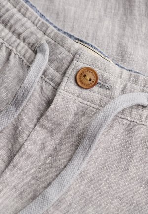 Pantalon en lin gris clair avec un bouton en bois marqué « Superdry » et des cordons blancs à la taille.