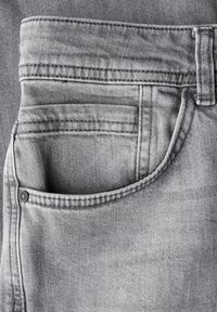 Jeans de mezclilla gris con un bolsillo delantero, con costura diagonal, un remache metálico y un acabado liso, ligeramente deslavado.