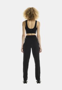 Black athletic outfit featuring a fitted sports bra and tapered pants with an elastic waistband, designed for comfort and mobility.