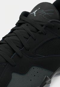 Μαύρο αθλητικό παπούτσι με υφή υφάσματος, με στοιχεία από διχτυωτό υλικό και λείες συνθετικές επικαλύψεις. Διαθέτει υπογραφή λογότυπο στη γλώσσα και σχέδιο με κορδόνια.