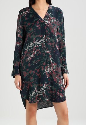 Vestido de manga larga en un patrón de camuflaje oscuro, que presenta tonos de verde, burdeos y gris. Escote en V y dobladillo asimétrico. Tejido suave.