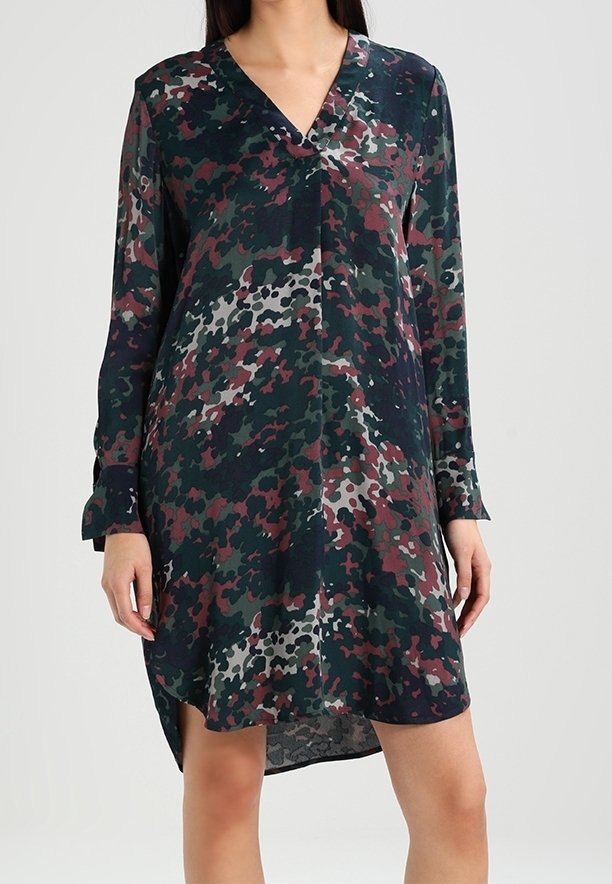 Vestido de manga larga en un patrón de camuflaje oscuro, que presenta tonos de verde, burdeos y gris. Escote en V y dobladillo asimétrico. Tejido suave.