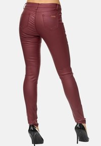 Bordeaux nep leren skinny broeken met een hoge taille en achterzakken, gecombineerd met zwarte hoge hakken, die een gladde glanzende textuur laten zien.