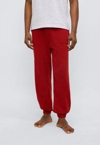 Κόκκινο παντελόνι φόρμας με άνετη εφαρμογή, ελαστικά τελειώματα και δύο πλαϊνές τσέπες. Κατασκευασμένο από μαλακό ύφασμα, με διακριτικό λογότυπο μάρκας στην πίσω τσέπη.
