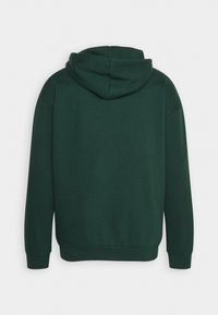 Sweat à capuche vert foncé vu de dos avec manches longues et taille ajustée.