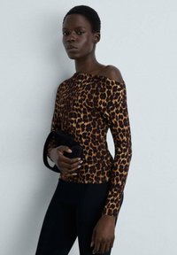 Halenka s leopardím vzorem, dlouhý rukáv, vyrobena z jemné látky, s odhalenými rameny. V kombinaci s malou tmavou kabelkou a černými přiléhavými kalhotami.