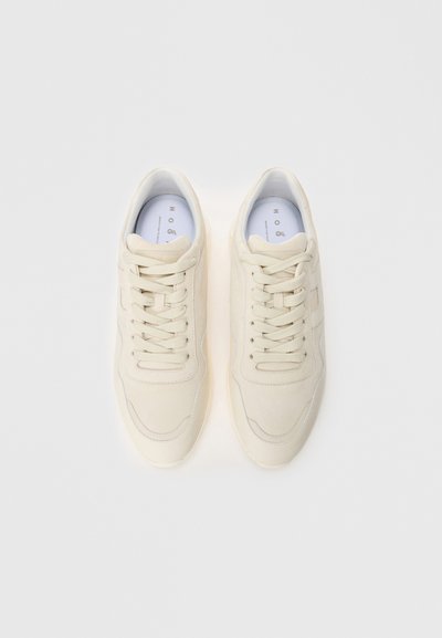 Pair of clean, off-white sneakers with laces, shown from above on a plain white background.