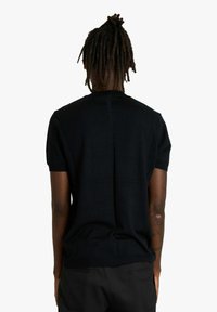 Maglione nero a maniche corte con scollo rotondo, realizzato in materiale morbido con un design aderente e cuciture minime, che mostra una vista posteriore pulita e semplice.