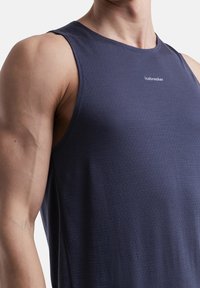 Marineblaues ärmelloses Sporttanktop aus strukturiertem Stoff mit einem dezenten Logo in der Mitte, entworfen für eine figurbetonte Passform.