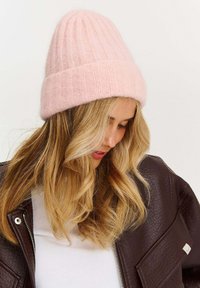 Ružová pletená čiapka s rebrovanou textúrou a voľným strihom. Materiál pôsobí mäkko a teplo, ideálny na chladné počasie.
