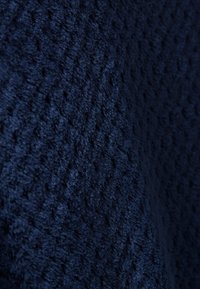 Tessuto di un blu navy con una superficie morbida e pelosa, caratterizzato da un sottile motivo in rilievo. Adatto per tappezzeria o abbigliamento.
