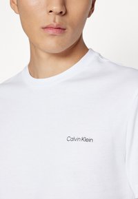 Calvin Klein ANGLED BACK LOGO - Apdrukāts T-krekls - bright white