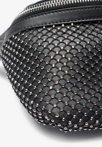 Borsa in faux leather nera con texture, caratterizzata da un motivo a diamond decorato con piccole borchie metalliche e una zip argentata nella parte superiore.