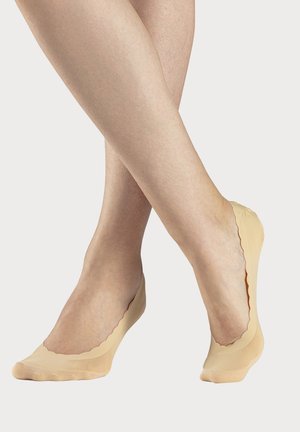 Nackte, nahtlose, unsichtbare Socken mit gewelltem Rand, aus einem glatten, dehnbaren Material gefertigt, das eng um den Fuß sitzt.