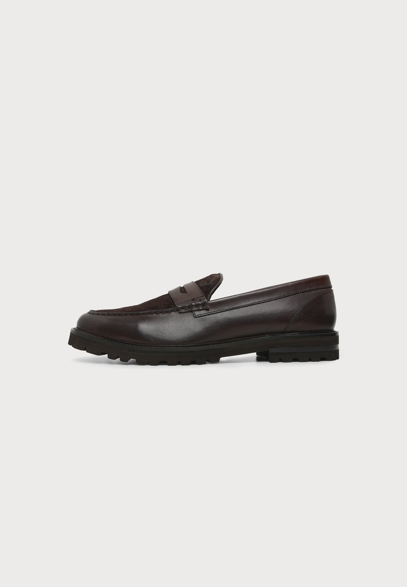 Mocassin penny en cuir et daim marron foncé avec semelle épaisse en caoutchouc noir, profil latéral sur fond blanc.