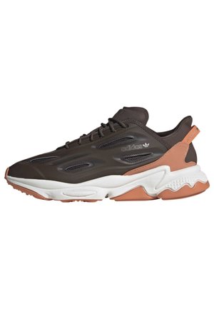 Lavtop Adidas-sneaker i mørkebrun med hvid og lysebrun sål, netpaneler på siden, snørelukning og trækstrop på hælen.