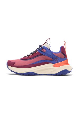 Multicolored sneaker featuring pink, purple, and orange panels, textured fabric, chunky cream sole, and a prominent logo on the side.