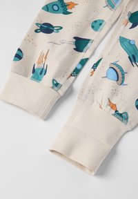 Beige Schlafanzughosen mit verspielten Raketen- und Planetenmotiven, mit elastischen Bündchen und kontrastierenden Nähten. Weicher, glatter Stoff.