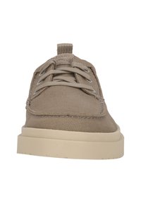 Beige lærredssko med rund tå, kontrasterende syninger og en blød, struktureret overdel. Har en robust cremet gummisål og snørebånd.
