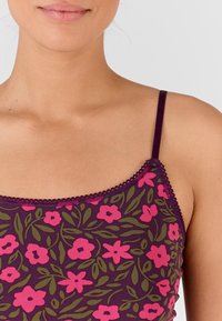 Top in tinta viola con un design floreale che presenta fiori rosa e foglie verdi, delicata rifinitura lungo il collo e le spalline, texture del tessuto morbida.