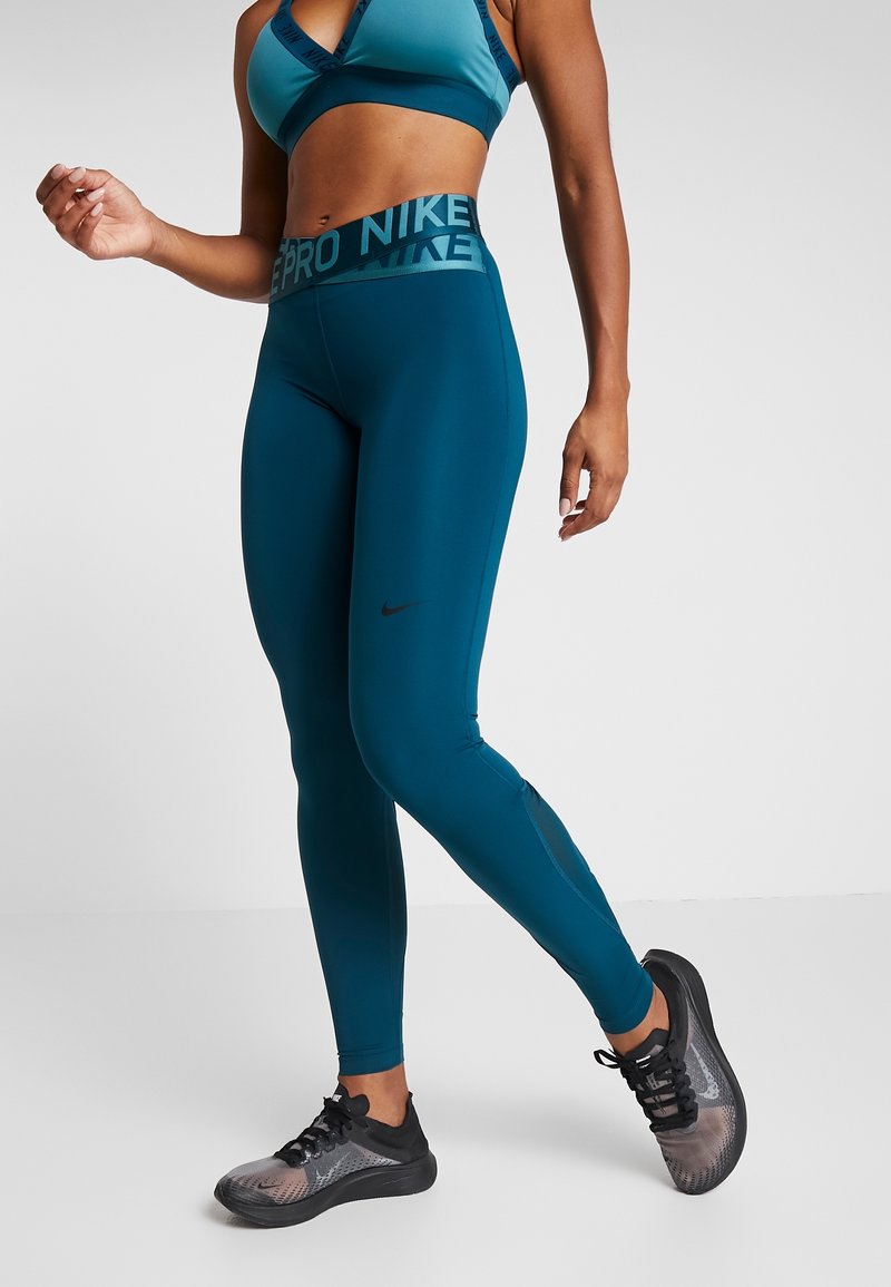 Siniset aktiiviset legginsit, joissa on tyylikäs muotoilu, leveä brändätty vyötärö ja tiukka istuvuus. Yhdistetty mustiin urheilujalkineisiin, joissa on teksturoitu pinta.