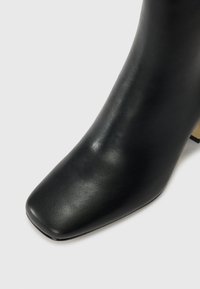 Black leather ankle boot with a square toe, smooth texture, and a chunky heel. No prominent patterns or hardware visible.