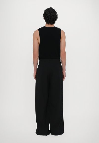 Black sleeveless top, paired with wide-legged black trousers. Smooth fabric with a relaxed fit. Minimalist design, no visible patterns or embellishments.