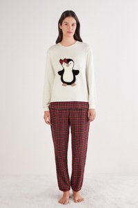 Sudadera blanca de manga larga con un aplique de pingüino; pantalones de pijama de cuadros rojos y negros con puños elásticos.