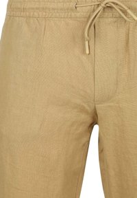 Lichtbeige linnen broek met een elastische tailleband en trekkoord. Heeft een gladde textuur en minimale naadafwerking.