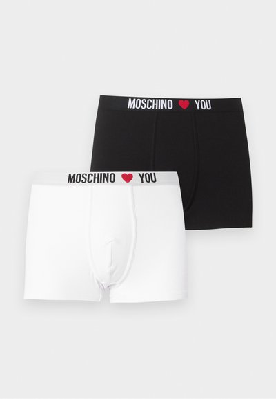To bokserbriefs, en sort og en hvid, hver med en linning med teksten "MOSCHINO" efterfulgt af et rødt hjerte og "YOU".