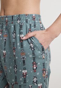 Turkosa pyjamasbyxor med mönster av nötkreatur och djur, med elastisk midja och sidofickor. Mjuk, strukturerad tyg.