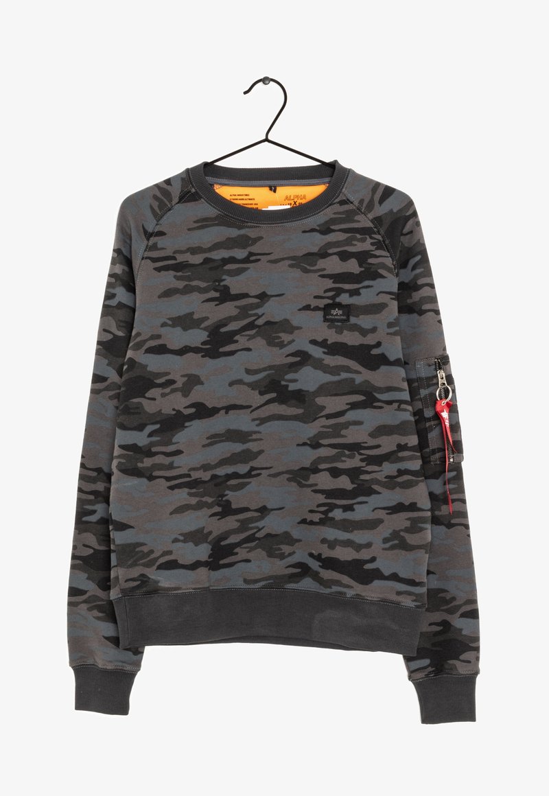 Sudadera de cuello redondo de manga larga con patrón de camuflaje en negro, gris y azul, bolsillo con cremallera y etiqueta roja en la manga izquierda, colgada en un percha negra.