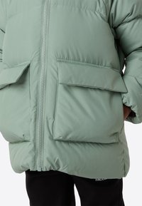 Mintgrøn dunjakke med lynlås foran og to store klaplommer. Blød tekstur og oversized design for varme.