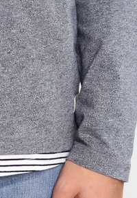 Grå sweatshirt med et struktureret stof, stribet kant og en tætsiddende ærmedesign. Strækbart materiale med et afslappet udseende.